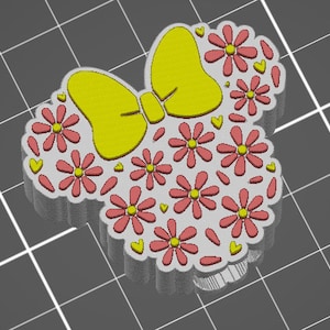 May include: A 3D printed design of a Minnie Mouse head with a yellow bow and pink flowers.