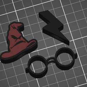Op de afbeelding: Drie zwarte 3D-geprinte Harry Potter-thema koekjesvormen. De vormen zijn in de vorm van een tovenaarshoed, een bliksem en een rond bril.