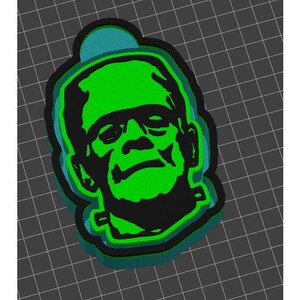 May include: A green and black 3D printed ornament shaped like Frankenstein's head.