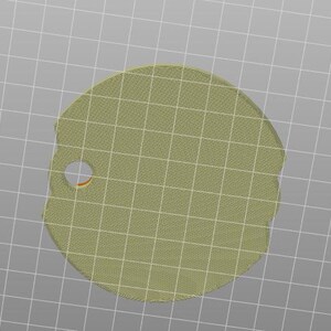May include: A light olive green, irregularly shaped tag with a small circular hole near the edge. The tag is set against a grid background.