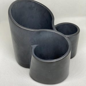 May include: A gray ceramic planter with three separate compartments. The planter has a unique, organic shape.