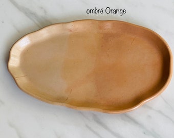 May include: A light brown oval ceramic tray with a wavy edge. The tray has an ombre effect, fading from a lighter brown to a darker brown.