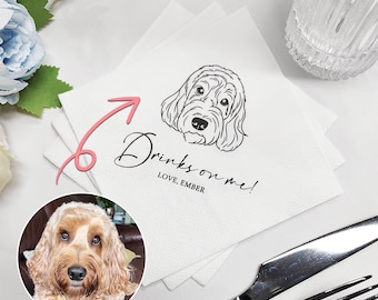 May include: White paper napkin with a black line drawing of a dog's head and the text "Drinks on me! Love, Ember".