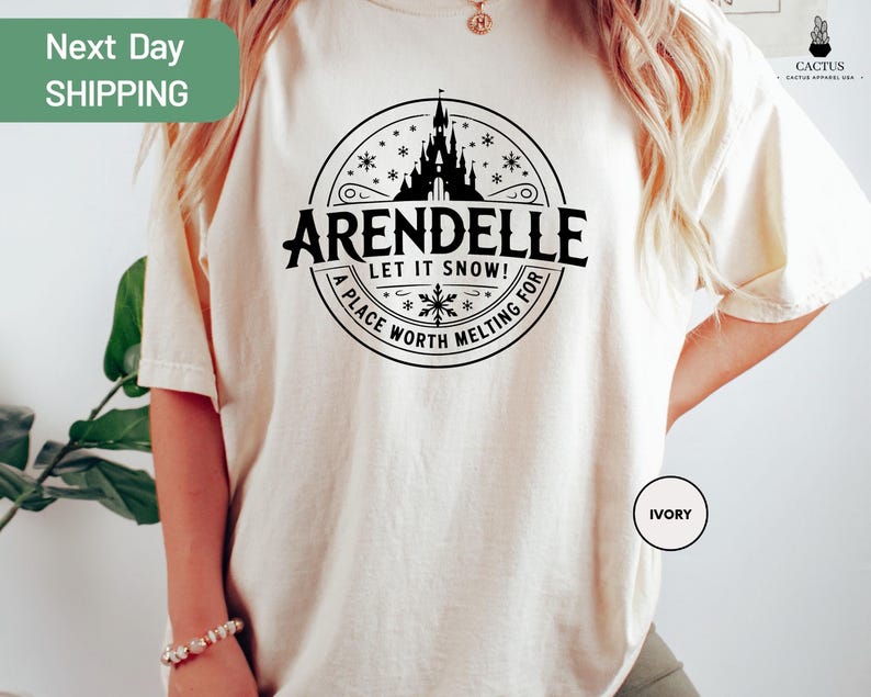 A person wearing a white t-shirt with a graphic design featuring a castle and snowflakes.