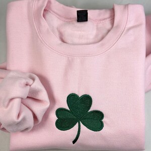 a pink shirt with a green shamrock on it