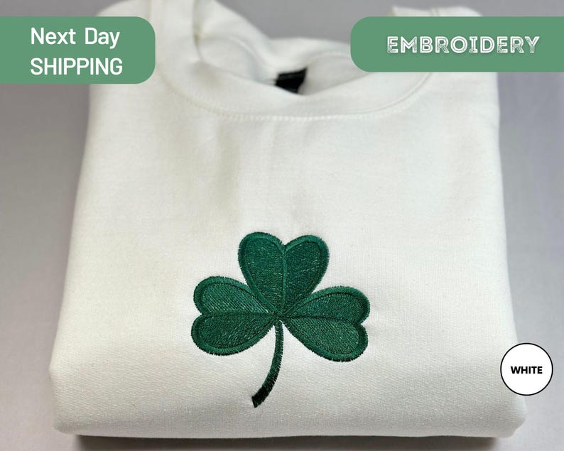a white t - shirt with a green clover embroidered on it