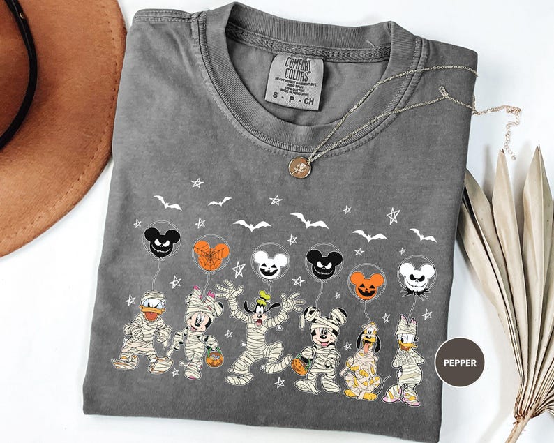 A gray t-shirt with a Halloween-themed design featuring various Disney characters such as Mickey Mouse, Minnie Mouse, Donald Duck, Goofy, and Pluto, along with bats, stars, and a pumpkin.