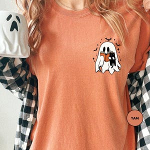 a woman holding a coffee mug with a ghost on it