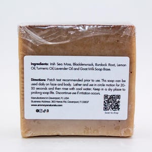May include: A bar of brown soap with a white label listing ingredients including Irish Sea Moss, Bladderwrack, Burdock Root, Lemon Oil, Turmeric Oil, Lavender Oil and Goat Milk Soap Base. The label also includes directions for use, a QR code, and the website address www.ammoyanaturals.com.