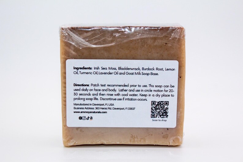 May include: A bar of brown soap with a white label listing ingredients including Irish Sea Moss, Bladderwrack, Burdock Root, Lemon Oil, Turmeric Oil, Lavender Oil and Goat Milk Soap Base. The label also includes directions for use, a QR code, and the website address www.ammoyanaturals.com.