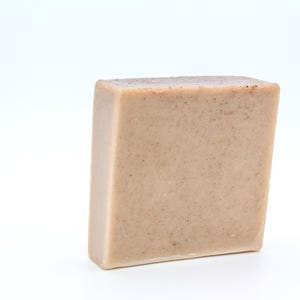 May include: A rectangular bar of light brown soap with a grainy texture.