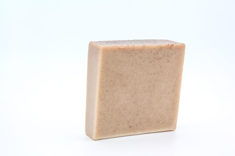 May include: A rectangular bar of light brown soap with a grainy texture.
