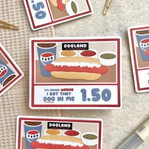 May include: A set of stickers featuring a cartoon hot dog with condiments, a soda, and the text "DOGLAND signature." The stickers also include the text "1/4 POUND WEENIE I GOT THAT DOG IN ME" and the price "1.50".