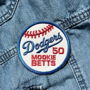 May include: A white and blue embroidered patch with a baseball and the text "Dodgers 50 Mookie Betts" in red and blue.