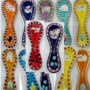May include: A collection of colorful ceramic spoon rests. Each rest features a unique animal design, including a horse, fish, octopus, and elephant. The spoon rests are painted in vibrant colors with decorative borders and floral accents.