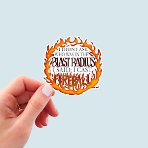 May include: A round sticker with a fiery orange and yellow design. The text on the sticker reads "I didn't ask who was in the blast radius I said: I cast fireball".