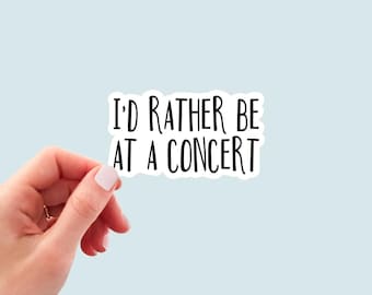 May include: White sticker with black text that reads "I'd rather be at a concert".
