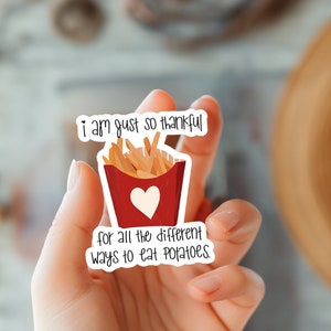 May include: A white sticker with a red and white cartoon image of a container of french fries with the text "i am just so thankful for all the different ways to eat potatoes."