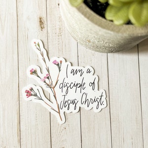 May include: A white sticker with a floral design and the text "I am a disciple of Jesus Christ."
