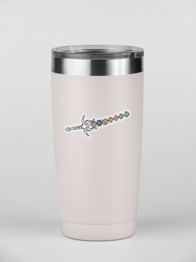 May include: A light pink insulated travel mug with a silver lid. A black and white line drawing of a sword with dice attached to the blade is on the front. The dice are various colours and shapes.
