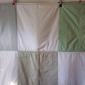 Könnte beinhalten: Eine Patchwork-Decke aus wiederverwendeten Hemden in Grün-, Weiß- und Hellblautönen. Die Decke ist mit einem dekorativen Stich zusammengenäht.