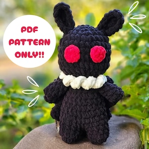 May include: A black crocheted creature with red eyes and a white collar. The plushie has long ears and small wings. The text "PDF PATTERN ONLY!!" is in a white circle above the creature.