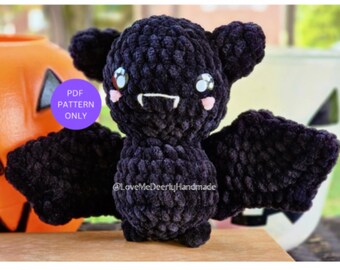 May include: A crocheted black bat plush toy with pink cheeks and white eyes. The bat has a small mouth with two white fangs. The text "PDF PATTERN ONLY" is in a purple circle on the left side of the image.