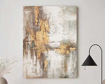 May include: Abstract painting with gold and brown accents on a white background. The painting has a textured look and is framed in a simple black frame.