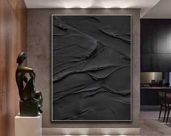 May include: A black and white abstract painting with thick brushstrokes and a textured surface. The painting is framed in a thin, gold frame and is hanging on a wall in a modern interior.