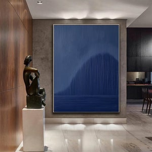 May include: Abstract painting with vertical lines in shades of blue, creating a wave-like pattern. The painting is framed and hanging on a wall in a modern interior.