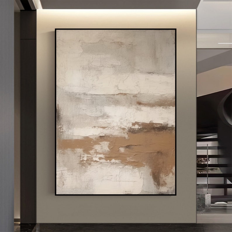 May include: Abstract painting with brown and white brushstrokes on a canvas. The painting is framed in a black frame and is hanging on a wall.