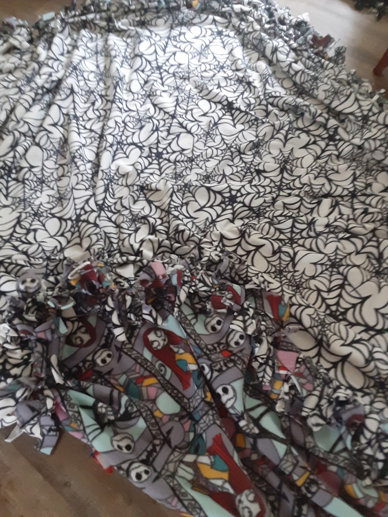 Puede incluir: Una manta de forro polar con tem&aacute;tica de Halloween con un dise&ntilde;o de telara&ntilde;a en blanco y negro y un dise&ntilde;o de patchwork colorido con personajes. La manta tiene un borde con flecos. Perfecto para la temporada de miedo.