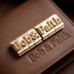 May include: Close-up of a brown leather wallet with the embossed text "Bob & Faith." Gold-colored metal letter stamps spell out "Bob & Faith" and are placed on top of the wallet.