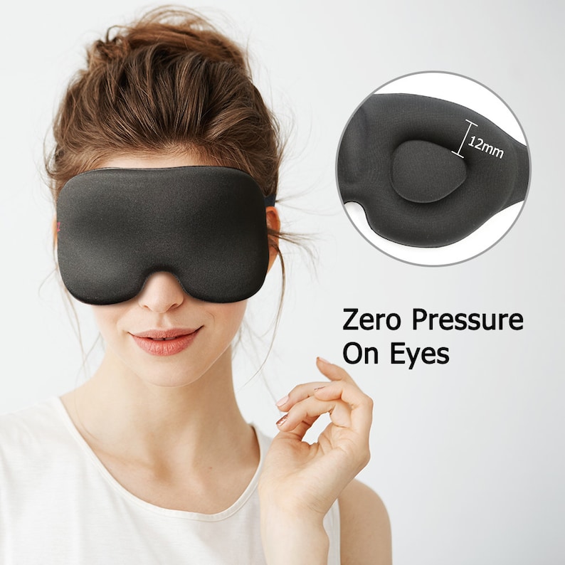 Op de afbeelding: Zwarte slaapmasker met een gecontourd ontwerp voor nul druk op de ogen. Het masker heeft een 12 mm dikke vulling voor comfort.