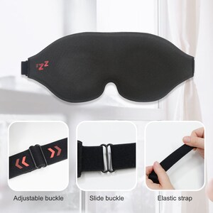 Op de afbeelding: Zwarte slaapmasker met verstelbare banden en een 'zzz'-logo. Het masker is gemaakt van zacht, comfortabel materiaal en is ontworpen om licht te blokkeren.