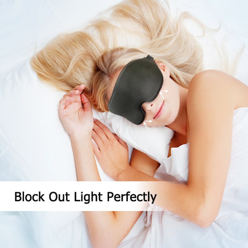 Op de afbeelding: Een persoon slaapt in bed met een zwart slaapmasker om licht te blokkeren. Het slaapmasker is gevormd om bij de ogen te passen en heeft een zacht, comfortabel gevoel.