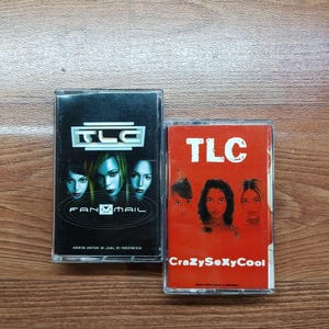 Op de afbeelding: Twee muziekcassettes van de band TLC. Eén heeft een zwarte hoes met "FanMail", de andere een rode hoes met "CrazySexyCool". Beide cassettes tonen het TLC-logo.