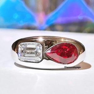 Puede incluir: Un anillo de plata con una piedra roja en forma de pera y una piedra transparente de forma cuadrada.