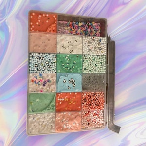 May include: A clear plastic container with 16 compartments filled with different types of slime and colorful beads.