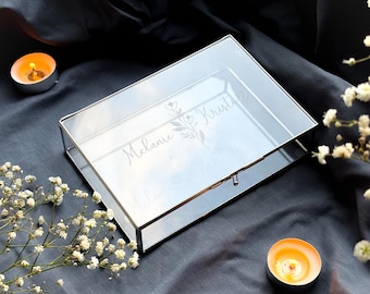 May include: A clear glass box with a silver metal frame. The box has a floral design and the names "Melanie" and "Krist" engraved on the lid.