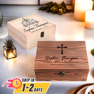 May include: Two wooden boxes with engraved crosses and the name "Sophia Thompson". The top box is light wood and says "Baptized" and "September 12, 2024". The bottom box is dark wood and says "First Holy Communion" and "September 12, 2024".