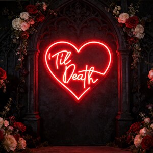 Peut inclure: Un enseigne en néon rouge en forme de cœur avec les mots "'Til Death" en écriture cursive. L'enseigne est montée sur un mur sombre et texturé, entourée d'arrangements floraux de roses rouges et blanches. Le thème général est romantique et gothique.
