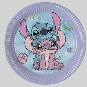 May include: A round paper plate with a light purple rim and a central illustration of the blue character Stitch standing behind the pink character Angel. The background features a light blue sky with small stars, a planet, and pink hibiscus flowers.
