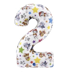 May include: A white number two balloon with a colorful Paw Patrol design. The balloon features images of the Paw Patrol characters, paw prints, and colorful stars. The balloon is designed for a birthday celebration.