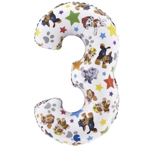 May include: A white number three balloon with a pattern of Paw Patrol characters, paw prints, and colorful stars. The balloon is inflated and ready for a birthday celebration.