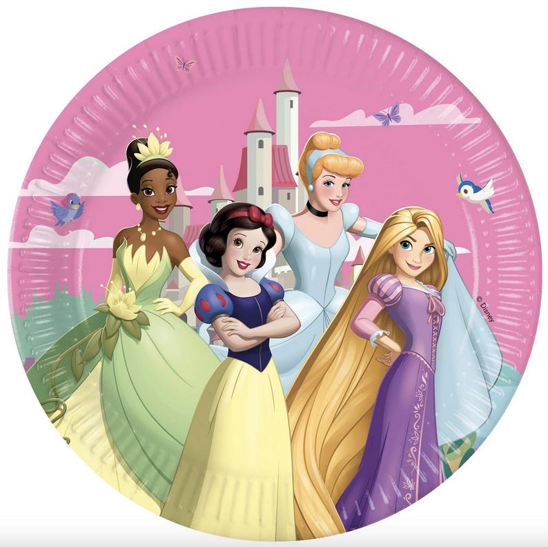 May include: A round paper plate featuring a pink background with a castle and four animated characters. Tiana wears a green dress, Snow White a blue and yellow dress, Cinderella a light blue gown, and Rapunzel a purple dress with long blonde hair.