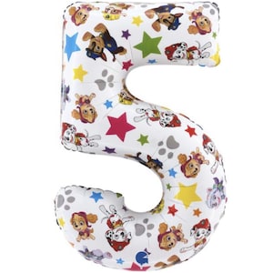 May include: White number 5 foil balloon featuring Paw Patrol characters, colorful stars, and paw prints. The balloon is designed for a birthday celebration or party.