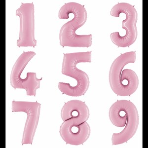 May include: A collection of nine individual light pink foil balloons shaped as the numbers one through nine. Each balloon features a smooth, inflated surface with subtle seam lines along the edges, arranged in a three-by-three grid format.