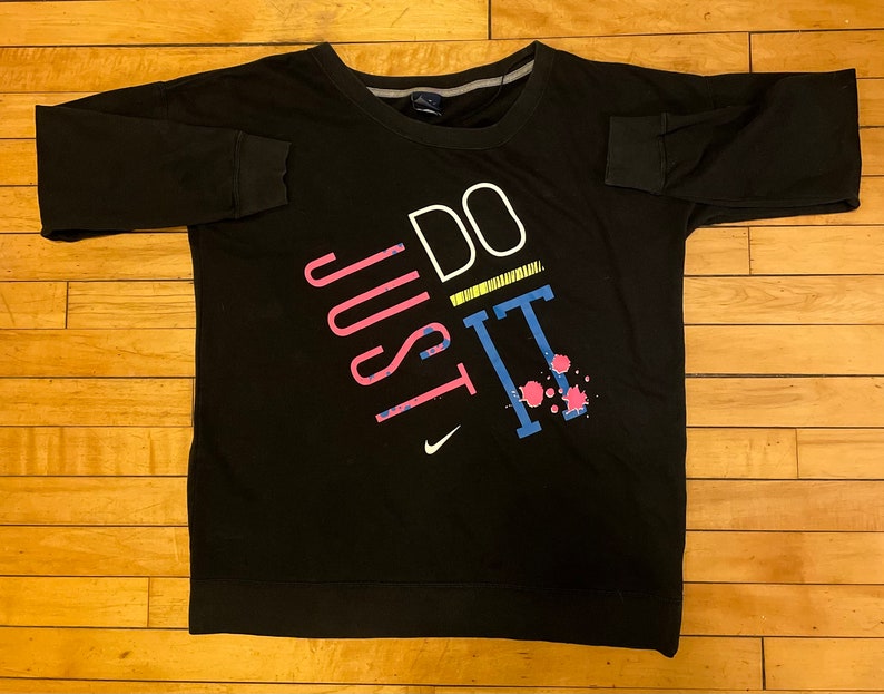 May include: Black long-sleeve sweatshirt with a white, pink, blue, and yellow graphic print that says "JUST DO IT".