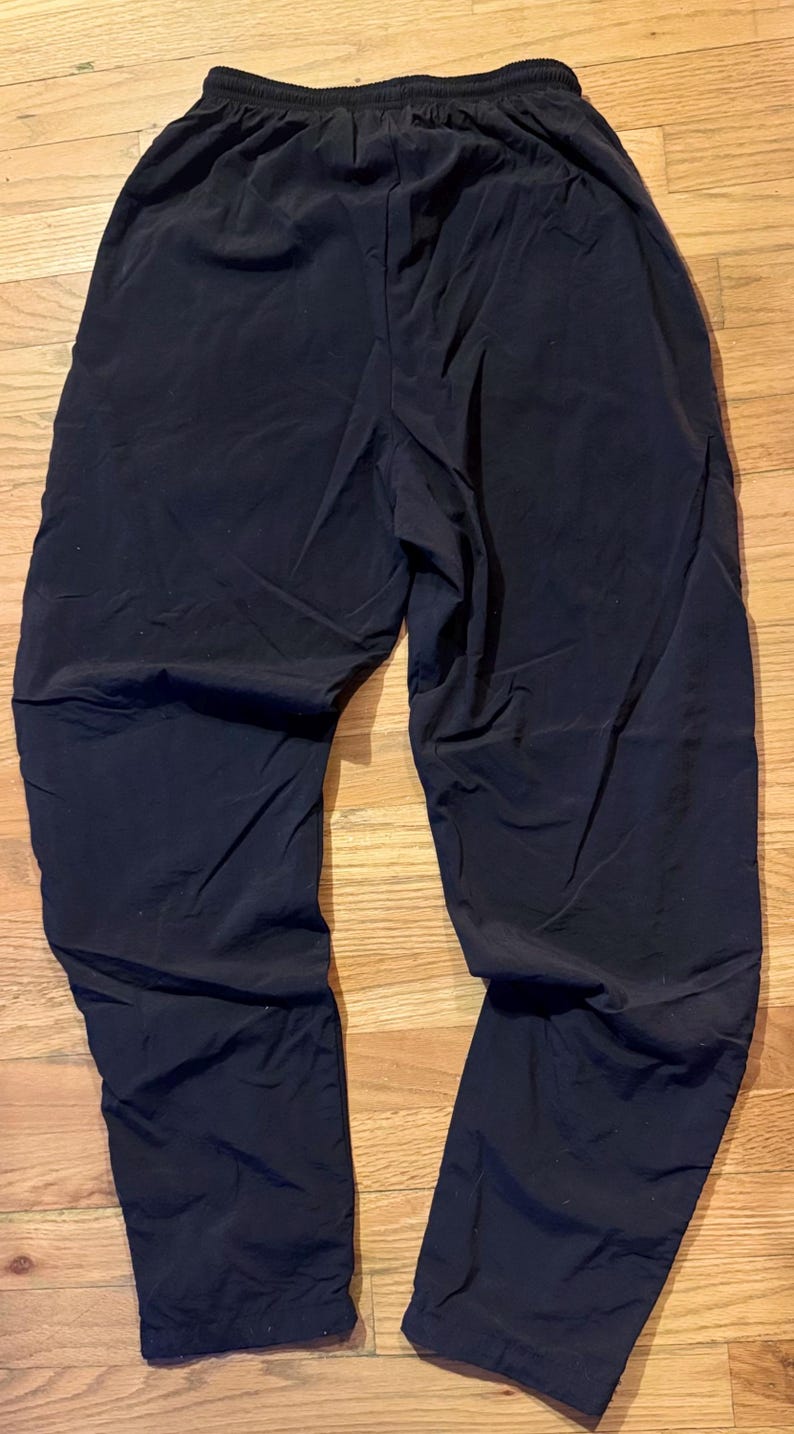 May include: Black athletic pants with an elastic waistband. The pants are made of a lightweight material and have a relaxed fit. The pants are suitable for various activities, including running, yoga, or casual wear.